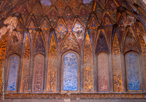 Stunning interior detail of the historic Wazir Khan Mosque in Lahore, Pakistan. Featuring magnificent Mughal frescoes, colorful kashi-kari tile work, and prominent Arabic calligraphy.