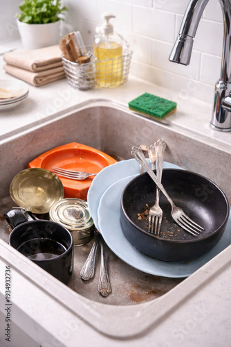 Dirty dishes in the kitchen sink after cooking—plates, bowls, cups, and cutlery before washing. 