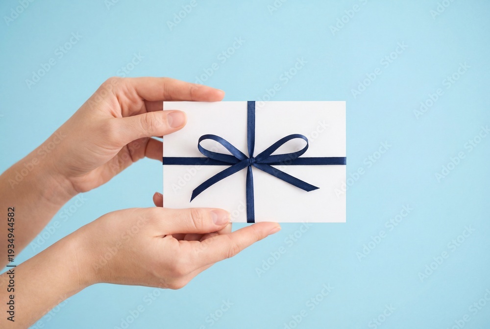 Obraz premium Woman hands holding white gift card with blue ribbon