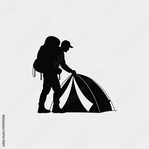 Silhouette of a hiker setting up a tent in a wilderness setting