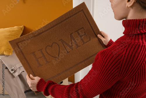 Young woman with doormat in...