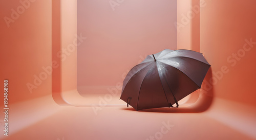 A closed dark umbrella with water droplets resting against a curved wall in a bright orange studio