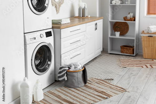 Interior of laundry room with washing machine, basket and shelf unit