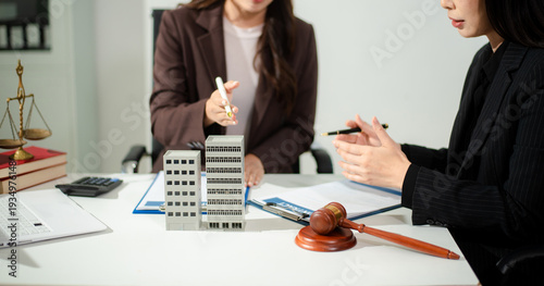 Real estate lawyer reviewing property contract with building model and gavel, concept of investment agreement, mortgage consultation, legal compliance