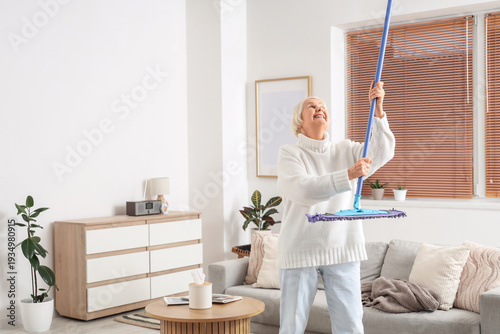 Senior woman with mop knock...