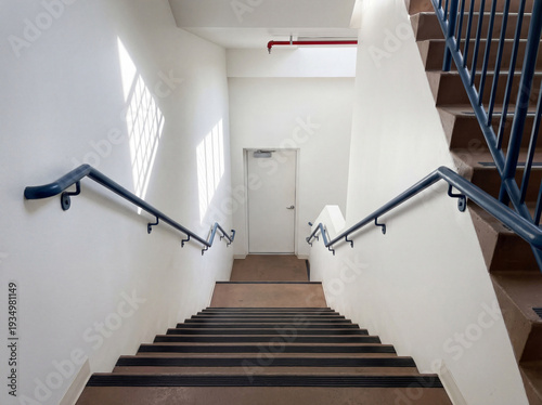 Looking down an empty indoor staircase toward a closed white door