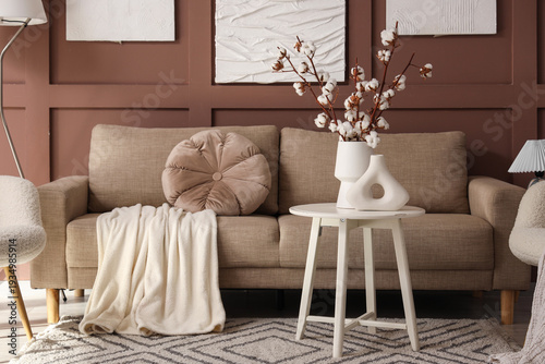Interior of stylish living room with grey sofa, table and cotton flowers in vase