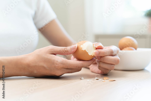 Foto Close-up shot of woman hands peeling shell of boiled egg on the table