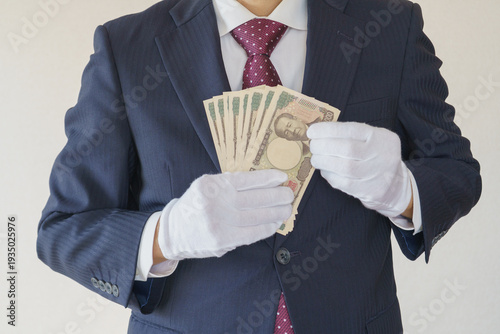 白手袋をはめて現金を数えるスーツ姿の男性