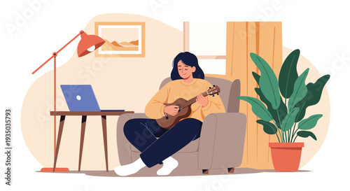 Young woman enjoys a relaxing moment at home while sitting in a cozy armchair and playing a ukulele near a laptop on a small desk by the window.