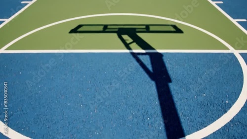 A basketball successfully goes through the hoop against a clear blue sky