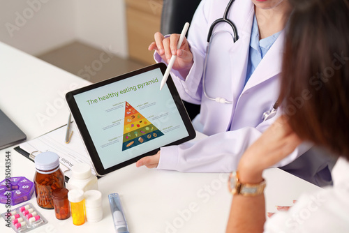 Healthcare Consultation. Doctor explaining healthy eating pyramid to patient using tablet.