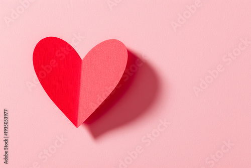 Handmade red and pink paper heart on pastel pink background for valentine's day or love themed designs and greeting cards