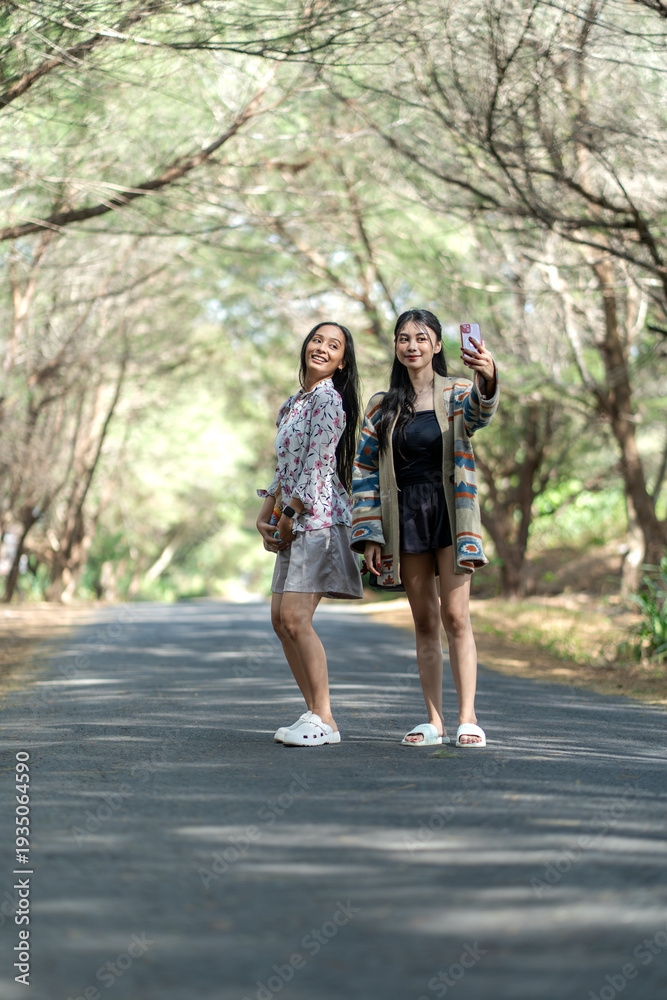 Fototapeta premium Asian Indonesian Women Friends Taking Selfie on Forest Road
