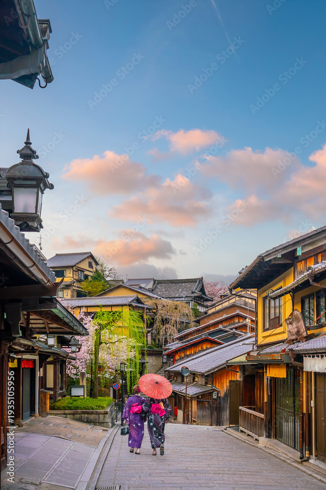 Obraz premium Traditional wooden houses, featuring a woman in a kimono surrounded by spring cherry blossoms in Kyoto