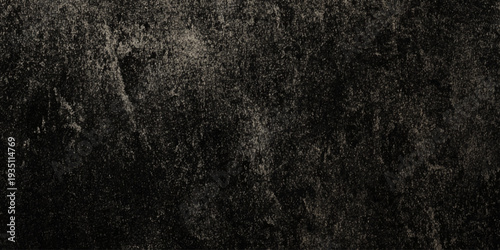 A dark textured background displaying a closely observed grainy surface with subtle variations in tone and light