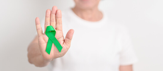 Elderly with Green Ribbon for concept of April Donate Life month, Organ Donation and Transplant Awareness, May Mental Health Awareness month and October Liver cancer. Health and world cancer day