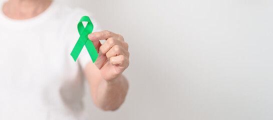 Elderly with Green Ribbon for concept of April Donate Life month, Organ Donation and Transplant Awareness, May Mental Health Awareness month and October Liver cancer. Health and world cancer day