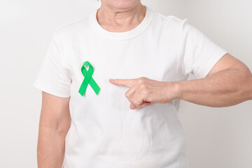Elderly with Green Ribbon for concept of April Donate Life month, Organ Donation and Transplant Awareness, May Mental Health Awareness month and October Liver cancer. Health and world cancer day