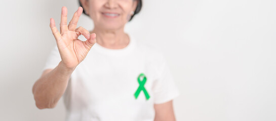 Elderly with Green Ribbon for concept of April Donate Life month, Organ Donation and Transplant Awareness, May Mental Health Awareness month and October Liver cancer. Health and world cancer day