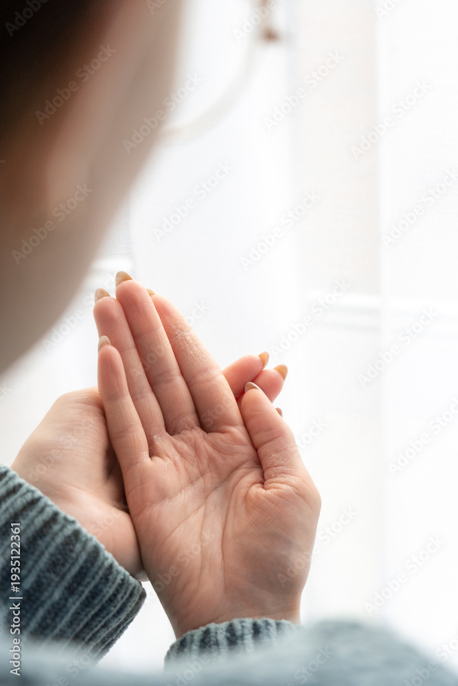 Naklejka premium Woman examining dry hands with skin irritation by window indoors 