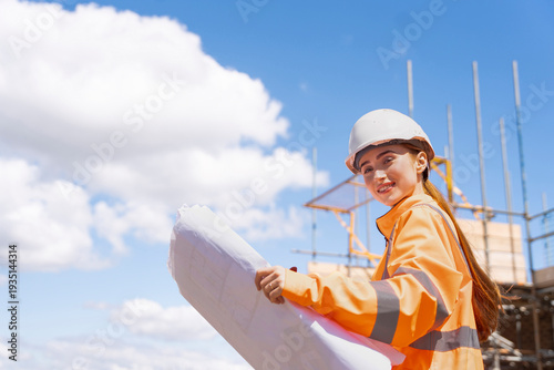 Builder woman working on construction site and using drawings to check works progress