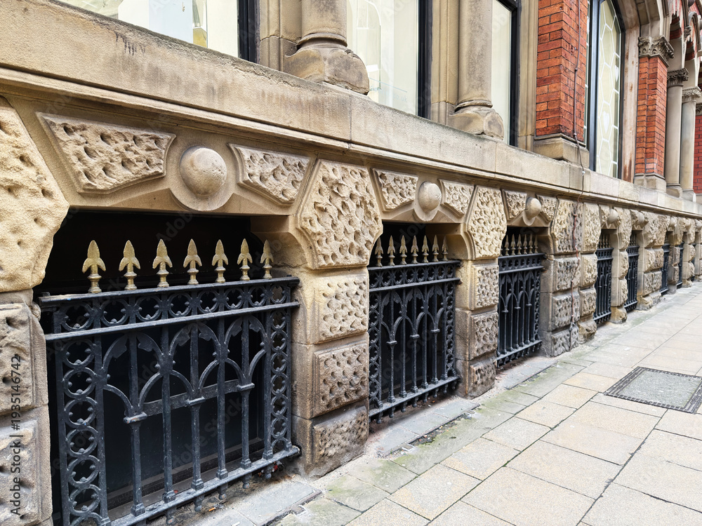 Obraz premium Historic stone building with ornate iron railings along a Manchester street in the UK