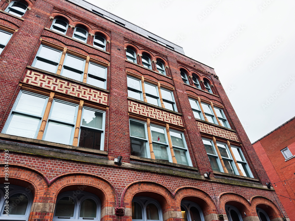 Fototapeta premium Brick building in Manchester, UK with arched windows and decorative facade in an urban street scene