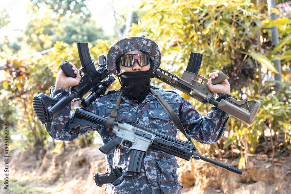 Obraz premium Confident soldier in camouflage uniform holding military rifle and weapon. tactical man in combat gear posing with gun outdoors, showing force and power