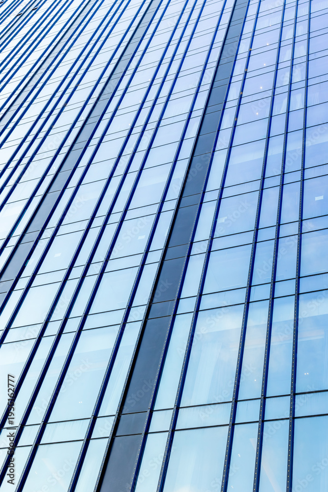 Obraz premium Tall glass curtain wall rising across urban office tower