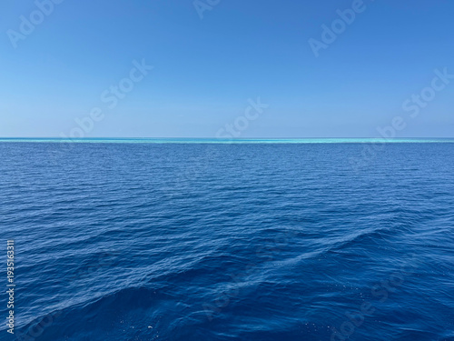 Photos Beautiful deep blue sea water surface with a small distant island on the horizon under a clear sky