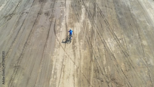 Aerial top top view of man sporty male Cyclist riding a bicycle on rural road background. Evening time.