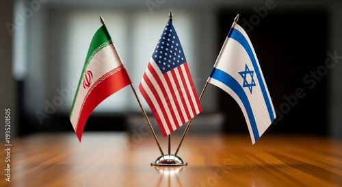 Three small flags of Iran, the United States, and Israel on a wooden table in a room