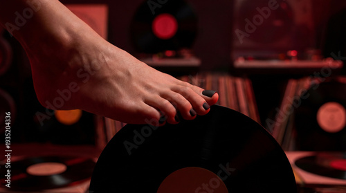 Vinyl records and foot on turntable showcase music experience in a home setting during evening hours