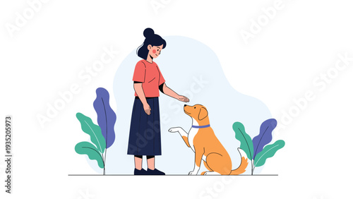 Young woman standing and training her pet dog to give a paw as a trick while interacting in an outdoor environment with plants.