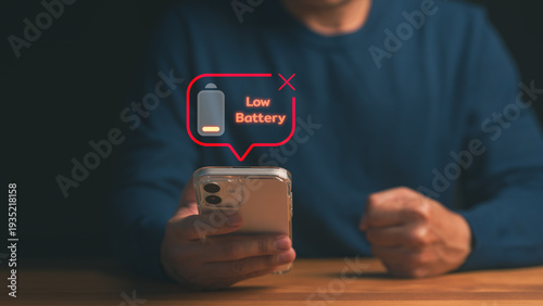 Frustrated man holding smartphone with low battery alert notification. Mobile phone out of power, empty energy icon, technology problem, charging stress and digital dependency concept.