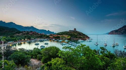 Beautiful calvi cityscape with harbor in foreground, corsica, france. high view of marina at dusk with boats reflecting in calm water and old city with citadel on hill background