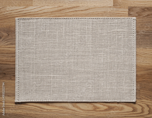 A beige fabric mat placed on a wooden surface viewed from directly above