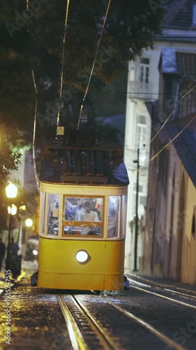 Yellow tram rides on rails at night in Lisbon