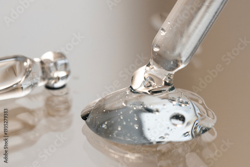 Dropper with cosmetic product in a drop of gel, serum on a beige background, front view.
