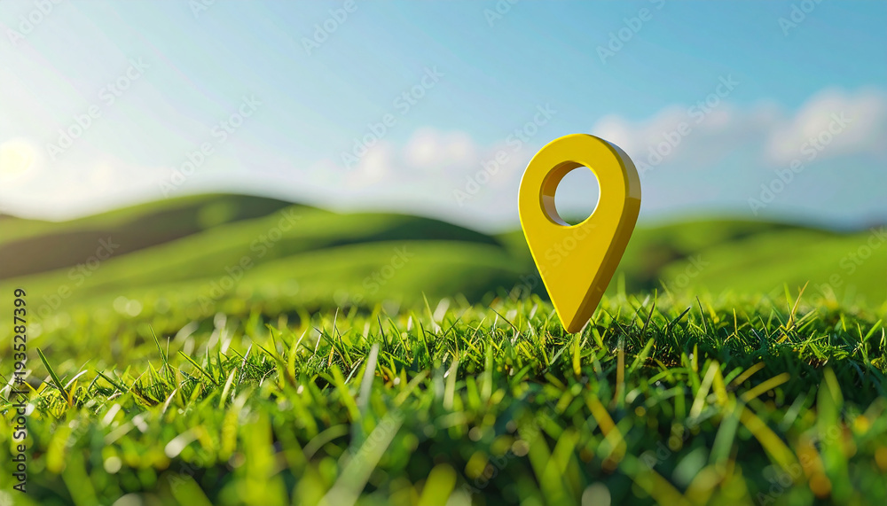 Fototapeta premium Vibrant yellow location pin standing in lush green grass, rolling hills and bright sky in background.