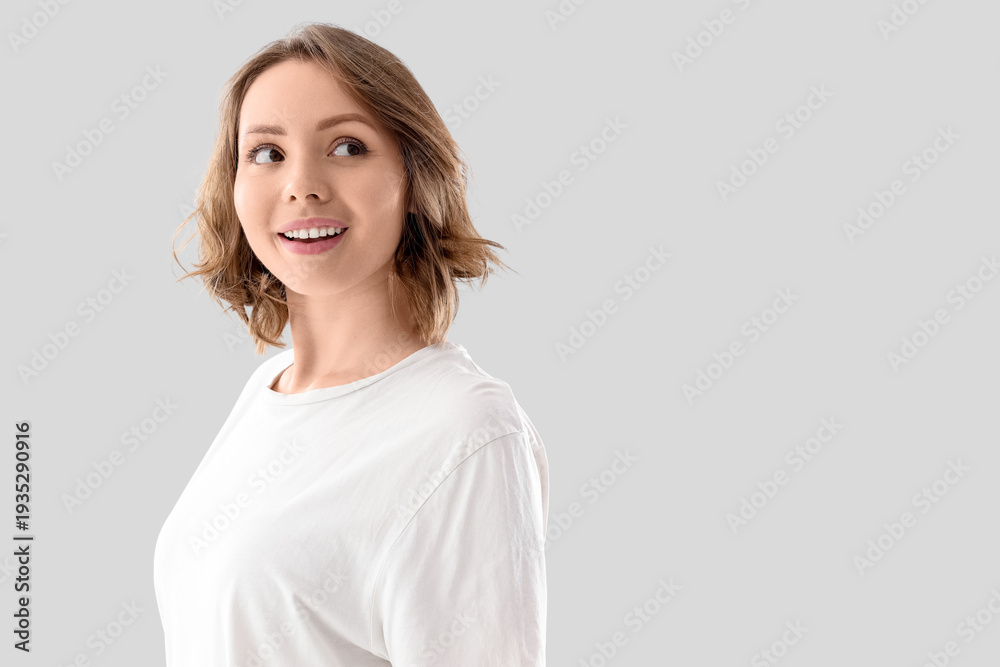Obraz premium Beautiful young woman with short curly hair on light background