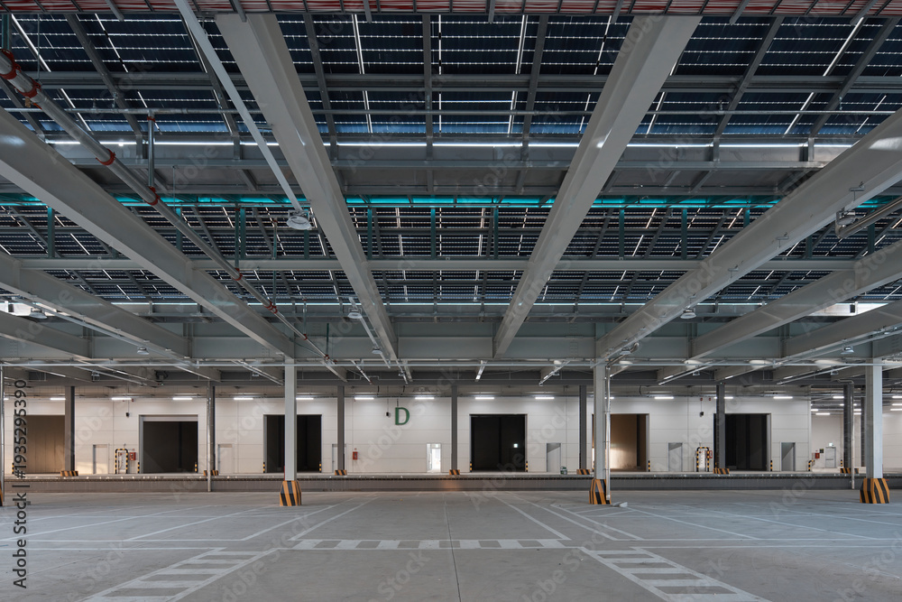 Fototapeta premium Empty large warehouse interior with concrete floor, columns, and industrial lighting.