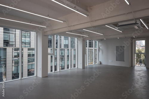 Empty modern office interior with desks, chairs, and large windows in a contemporary workspace.