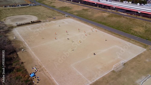 土手沿いのコートでサッカーをする少年を空撮　4K