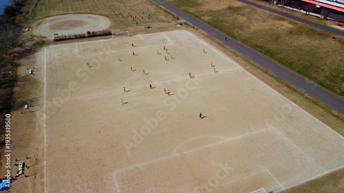 土手沿いのコートでサッカーをする少年を空撮　4K