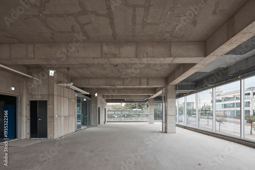 Quadro su tela Empty unfinished commercial interior with raw concrete ceiling, columns, and large windows