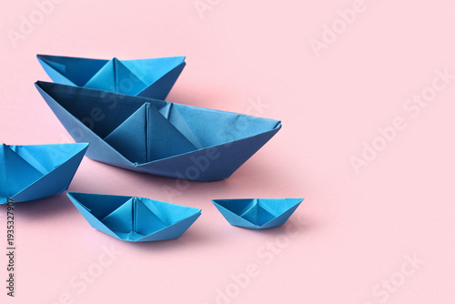 Blue paper boats on pink ba...