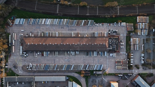 Aerial view of the FedEx Unit 24 warehouse with orderly rows of parked vehicles casting long shadows in the Holly Lane Industrial Estate, Atherstone, United Kingdom.