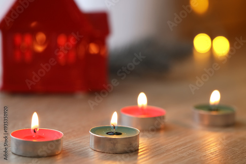 Burning candles on shelf in...